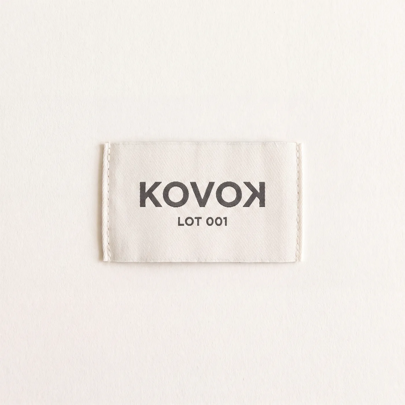 Cream woven neck label reading KOVOK LOT 001